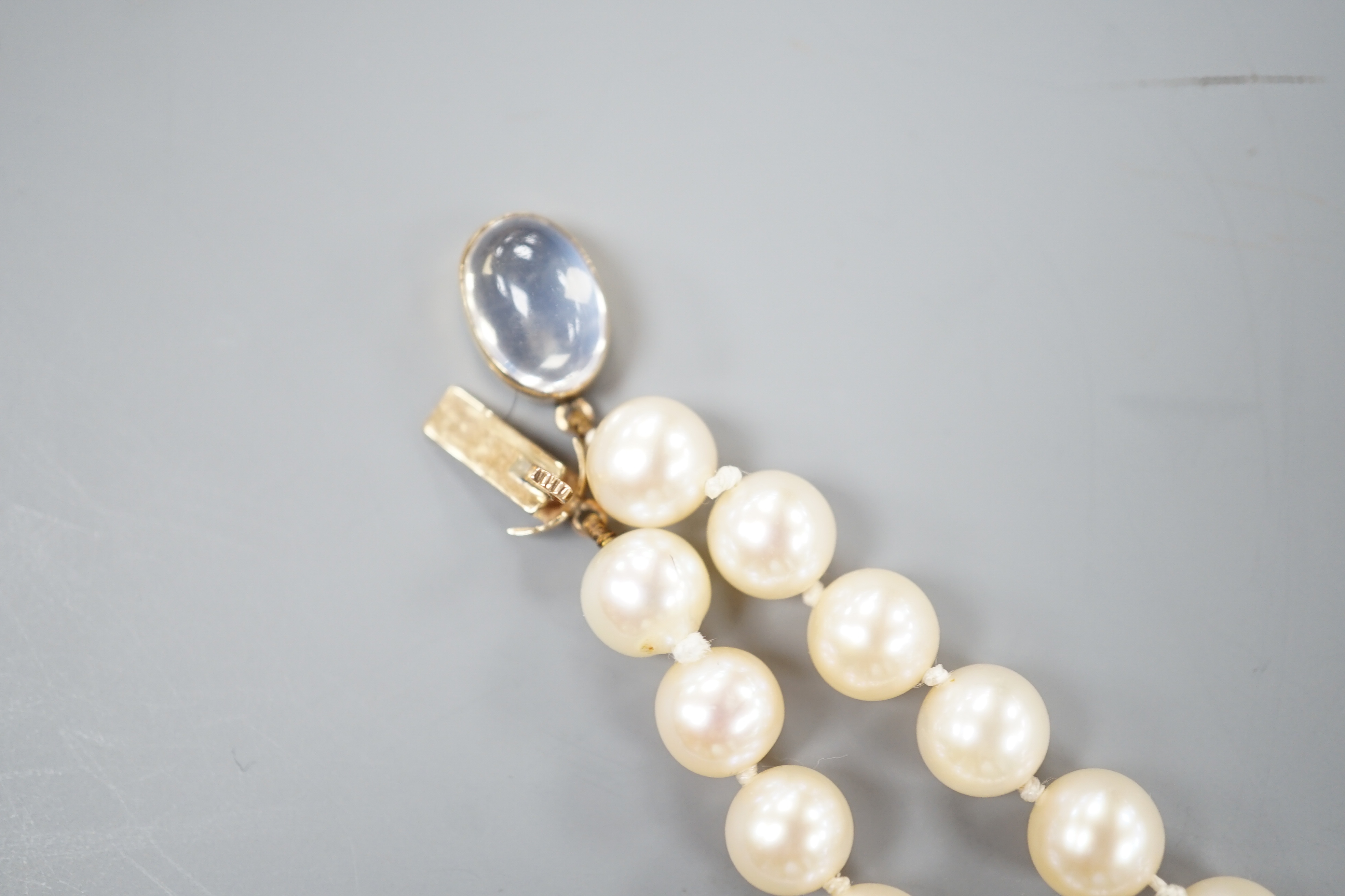 A single strand cultured pearl necklace, with yellow metal and moonstone set clasp, 56cm.